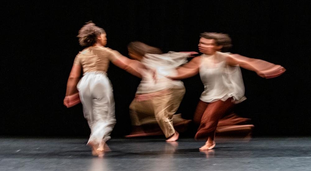Blurry photo showing three dancers in movement