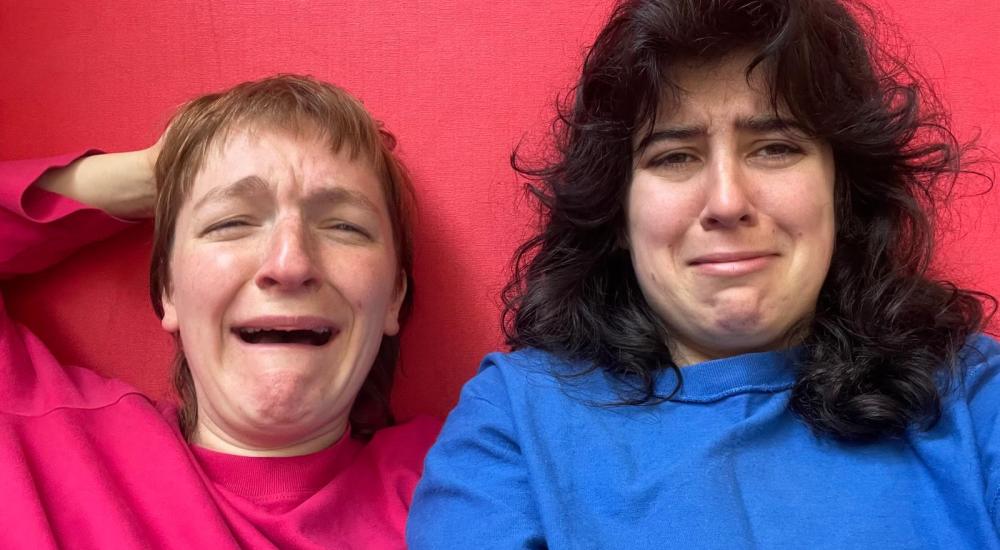 Two people crying in front of a red wall