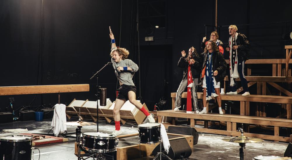 A performer jumping on a springboard while singing into a microphone