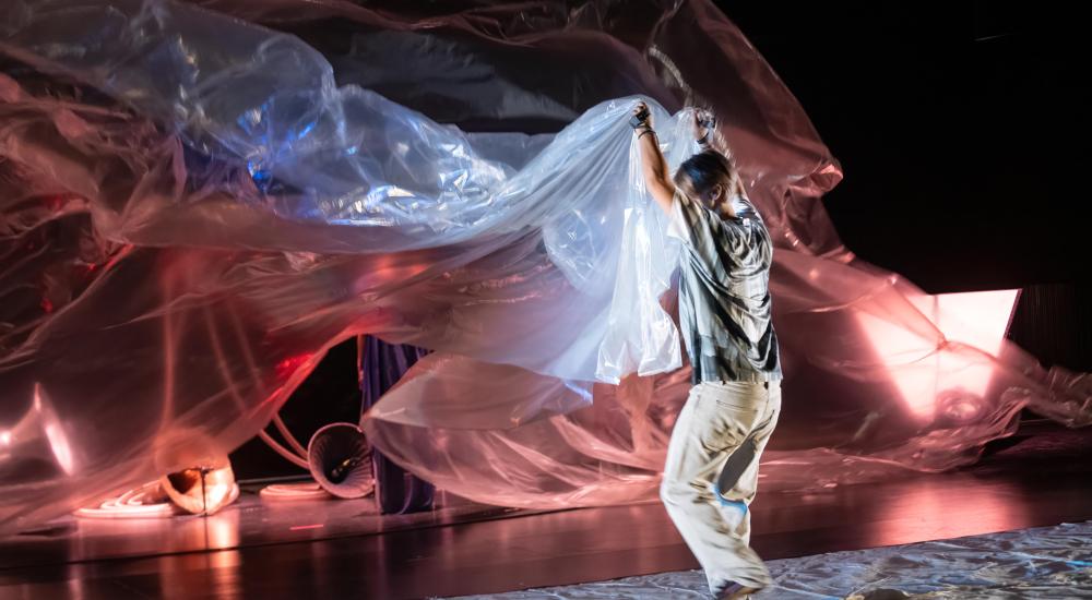 A performer holding up a big plastic screen with both hands