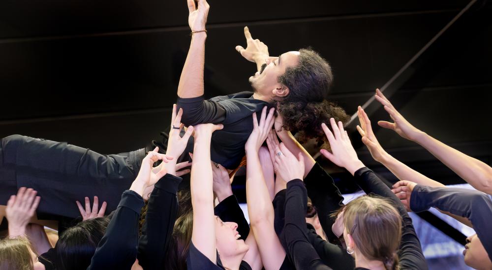 One performer being held up by a group of other performers