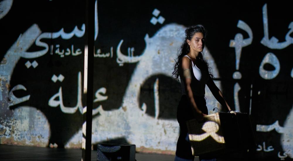 Marah standing in front of a wall with words in Arabic projected on it