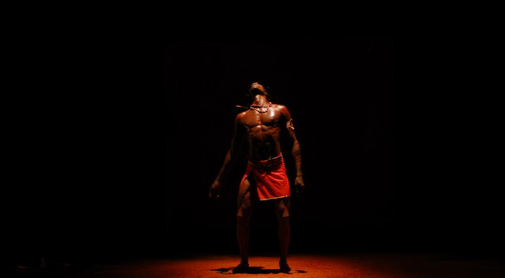 Fernando Anuang'a dressed in traditional Masai clothing under a spotlight