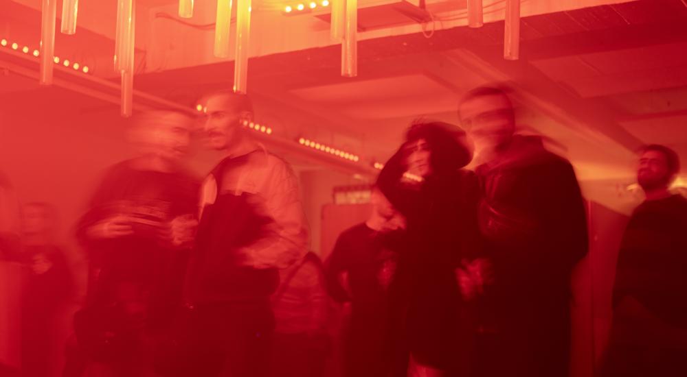 A blurry red picture of several people at last year's closing party