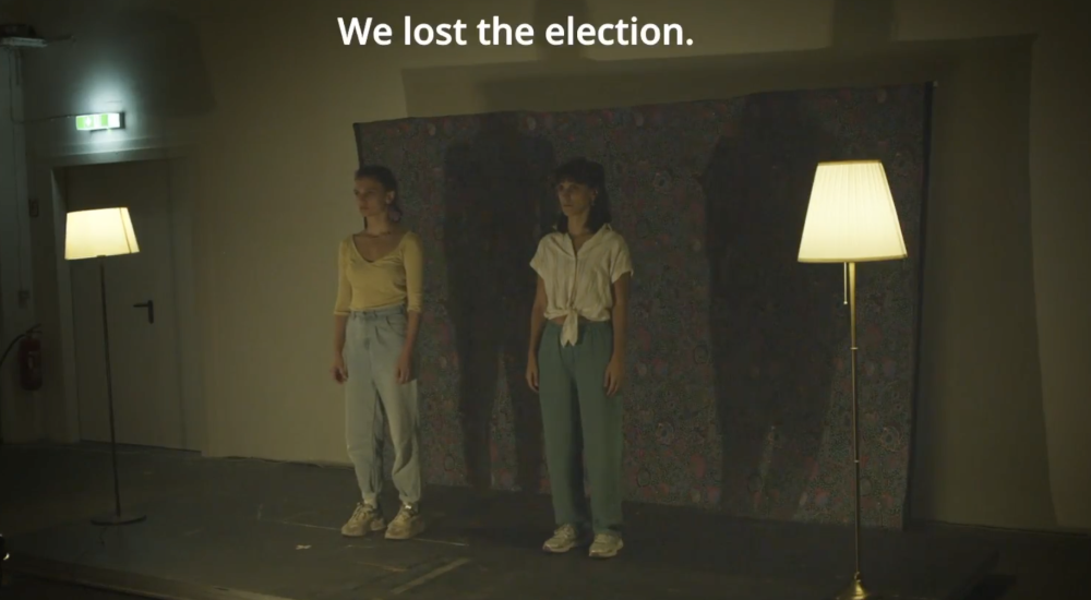 Two women standing in a sparsely lit room underneath the words "We lost the election."