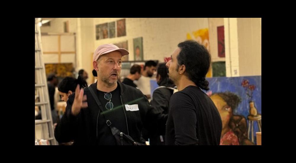 Two people talking in front of several artworks