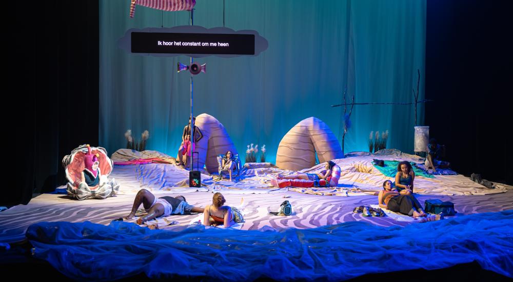 The full cast on stage, which has been transformed into a beach
