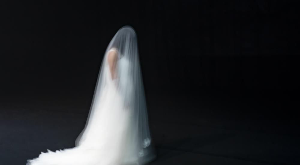 Desirée in a white wedding dress and large white veil