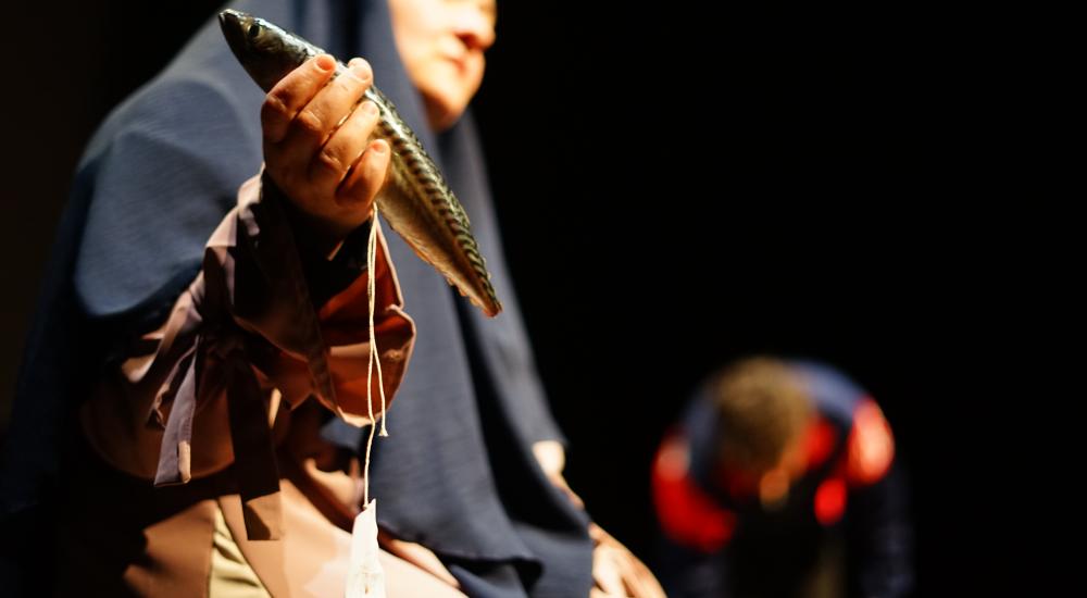 Someone wearing a headdress holding a fish