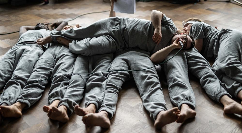 the dancers lying in a row with one of them lying on top of them across their bodies