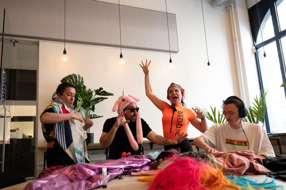 Four people trying on costumes and poses around a table