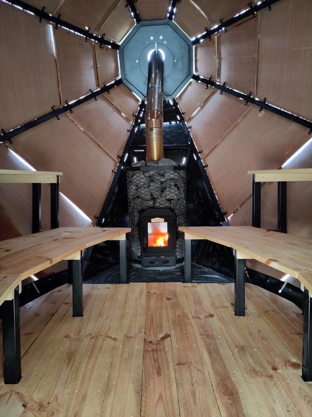 Inside the sauna: a wooden bench on either side and a fire in the middle