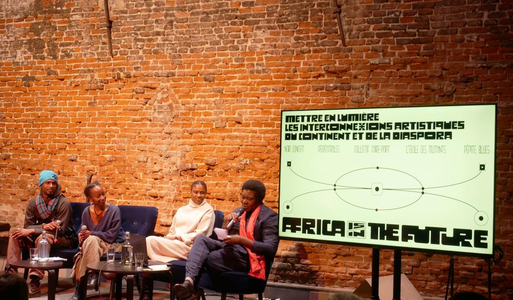 Four people on a panel next to a screen 