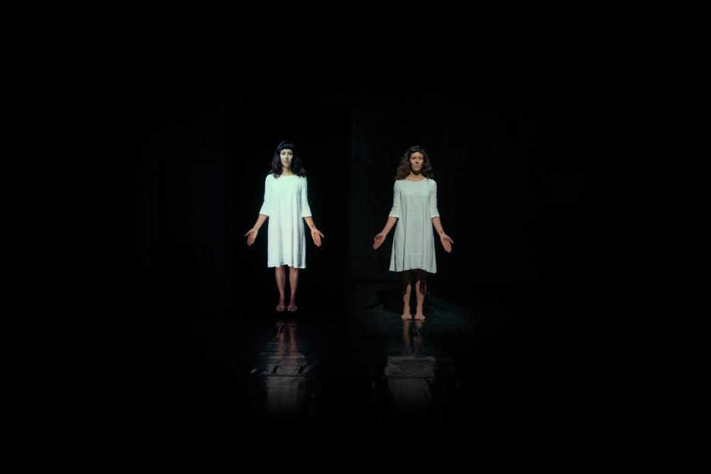 Two people in white dresses in a dark space