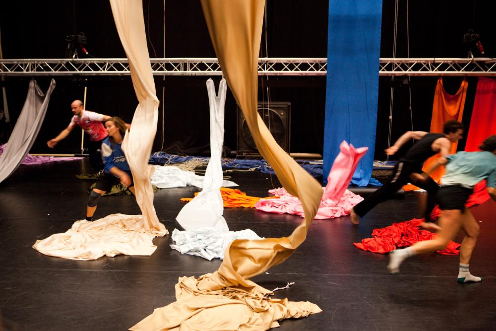 3 dancers running holding big coloured sheets