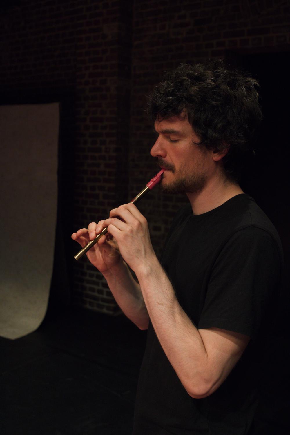 man with a flute in his mouth making music