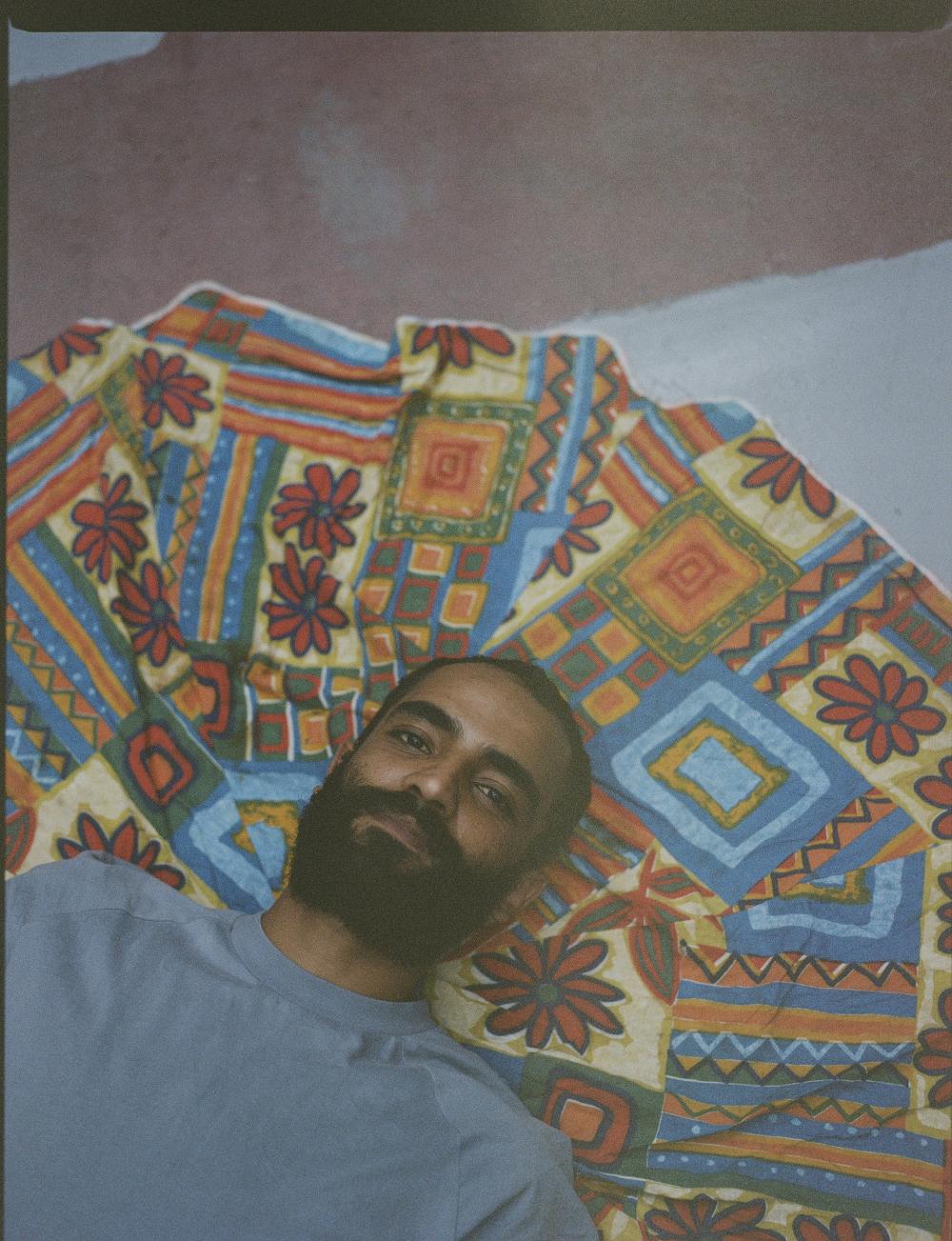 Fareed Aziz lying on a coloured rug