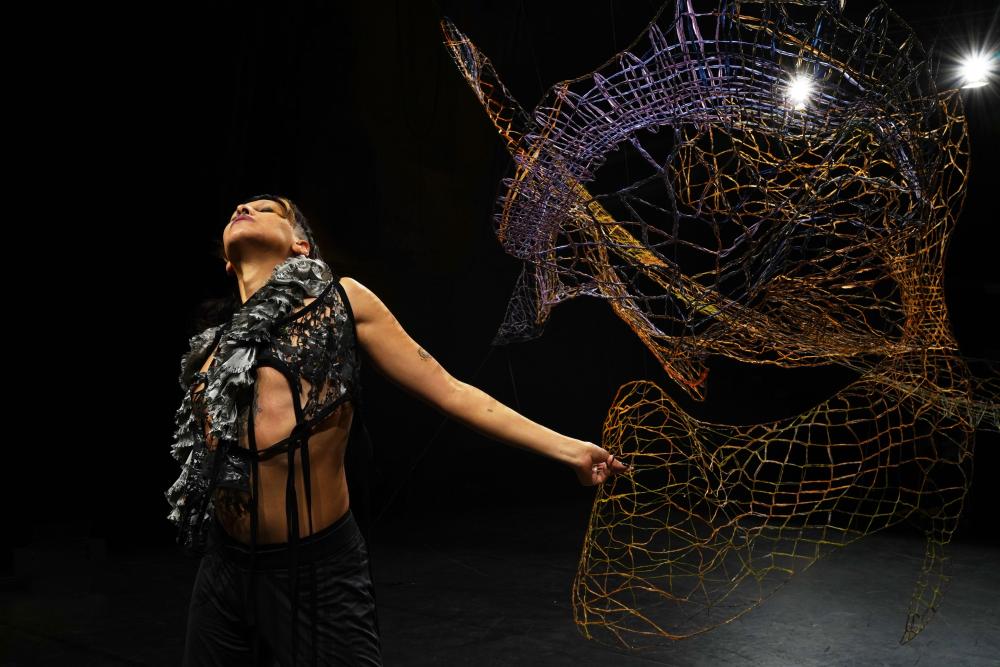 A dancer in front of a lace sculpture