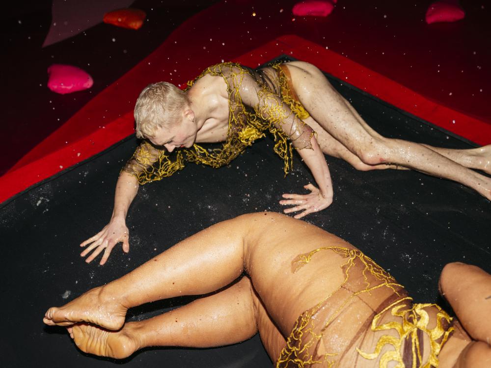 two performers laying on the floor, one of them crawling