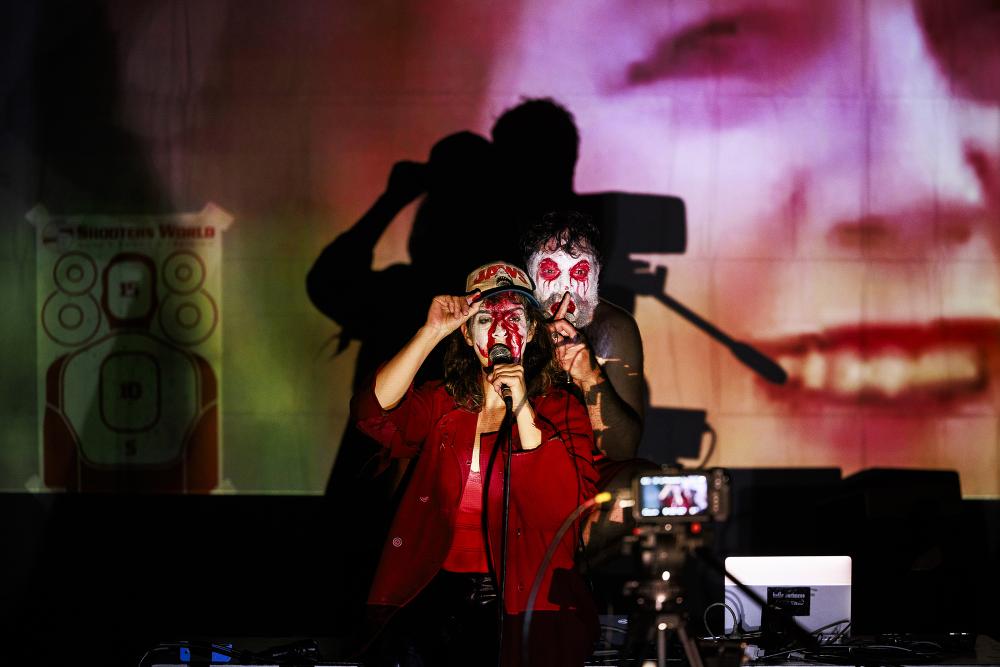 The two performers holding a finger to their lips