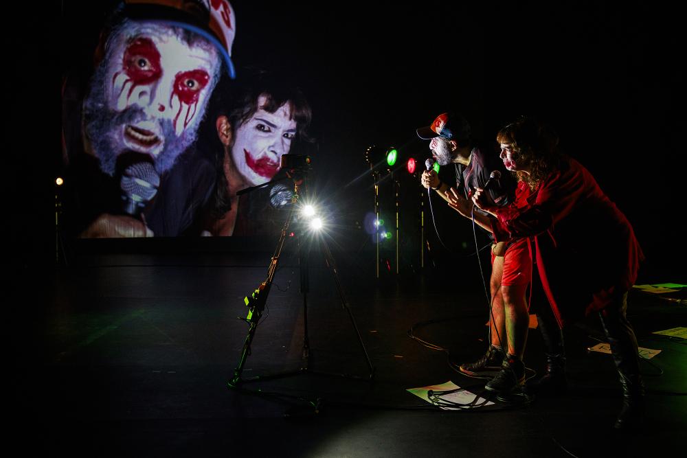 Rodrigo and Mariana looking into a camera whose feed is projected in front of them