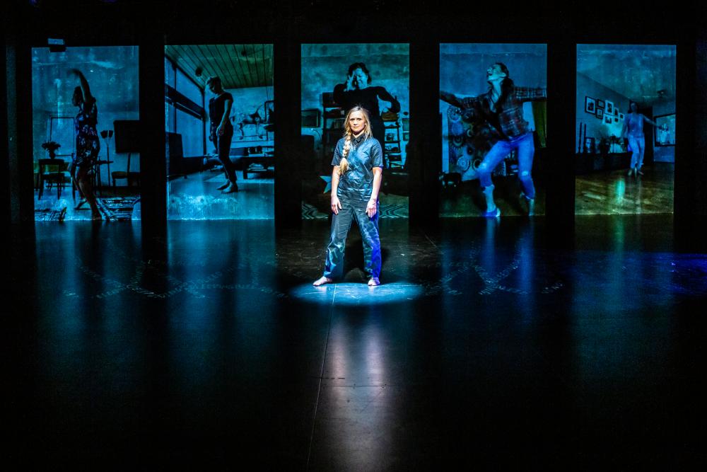Person standing in front of blue projections on a stage