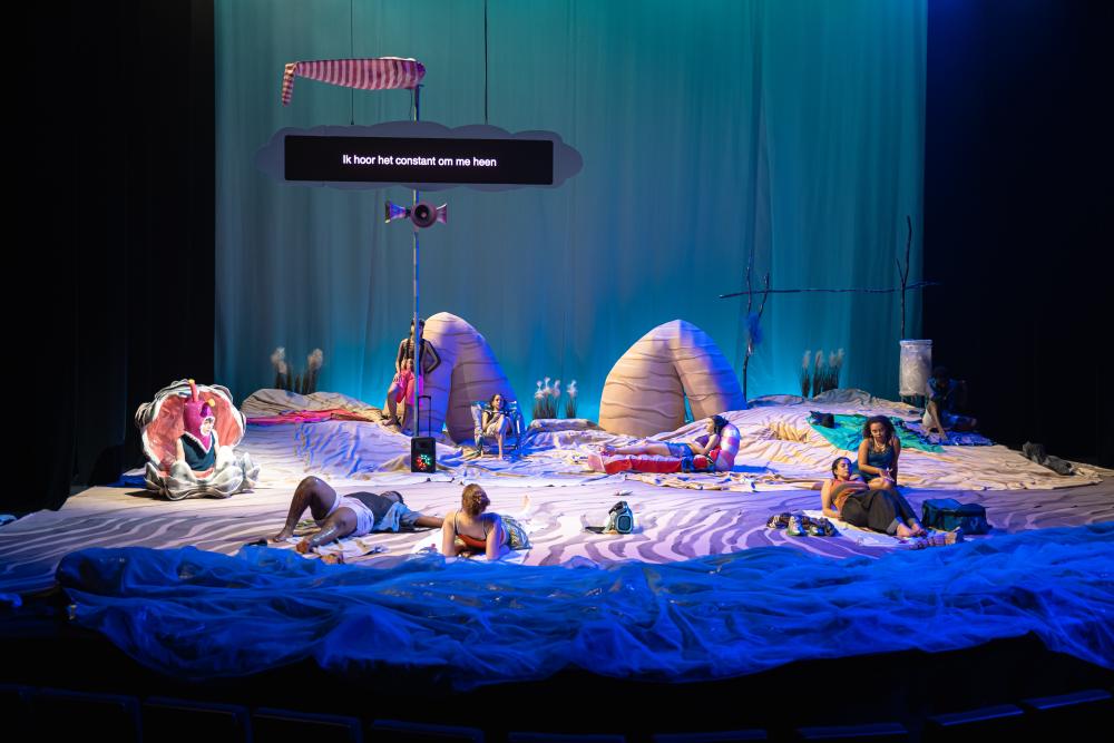 The full cast on stage, which has been transformed into a beach