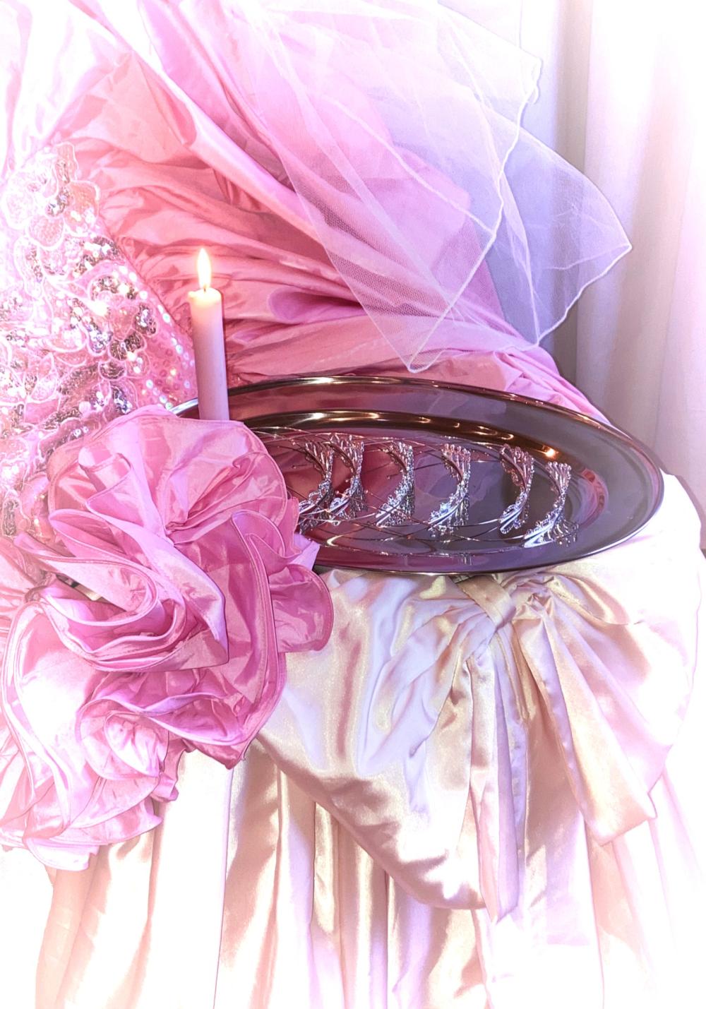 A candle on a plate resting on dresses