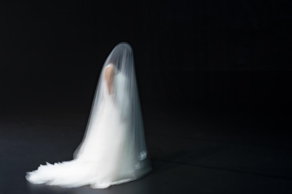 Desirée in a white wedding dress and large white veil