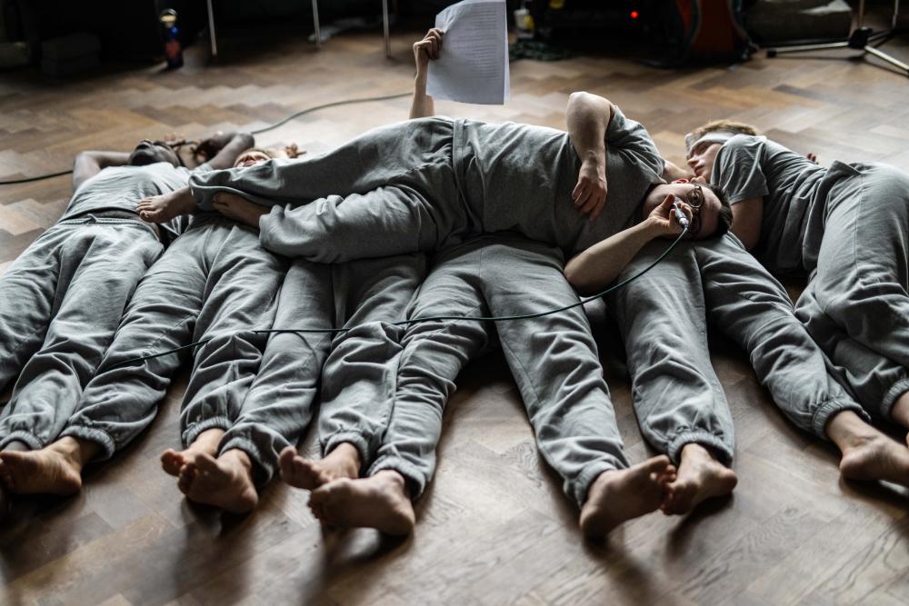 the dancers lying in a row with one of them lying on top of them across their bodies