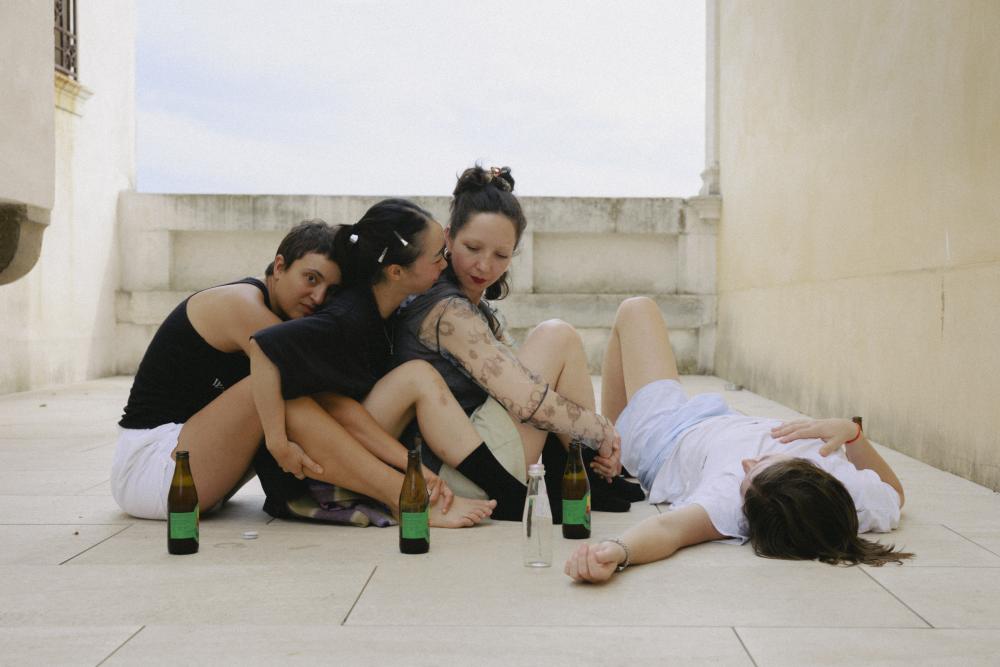 portrait of 4 performers sitting on the ground