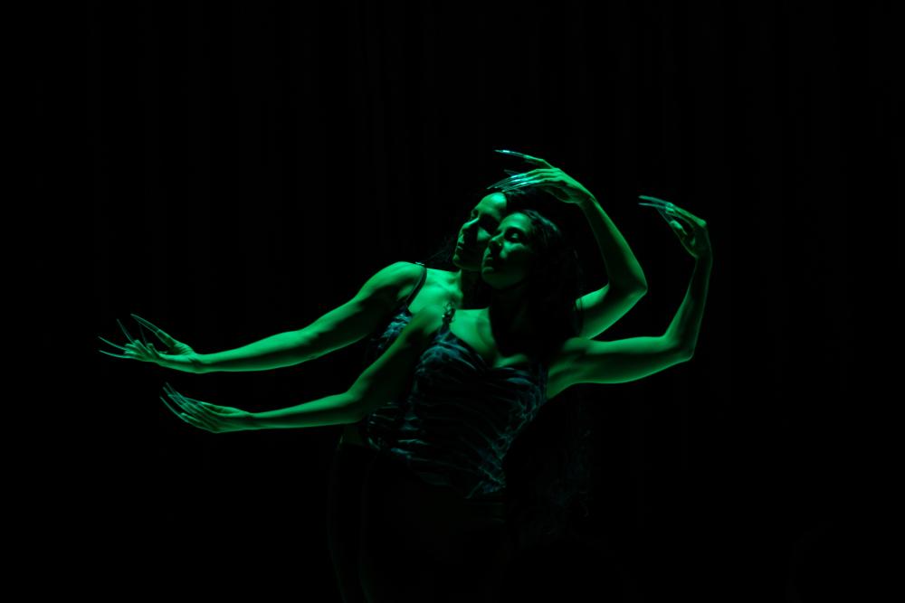 two dancers in green light with long nails