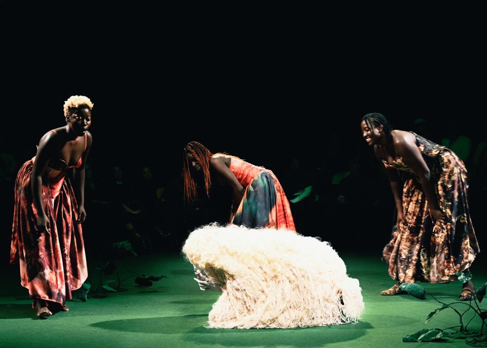 Three persons surrounding a sheep skin 