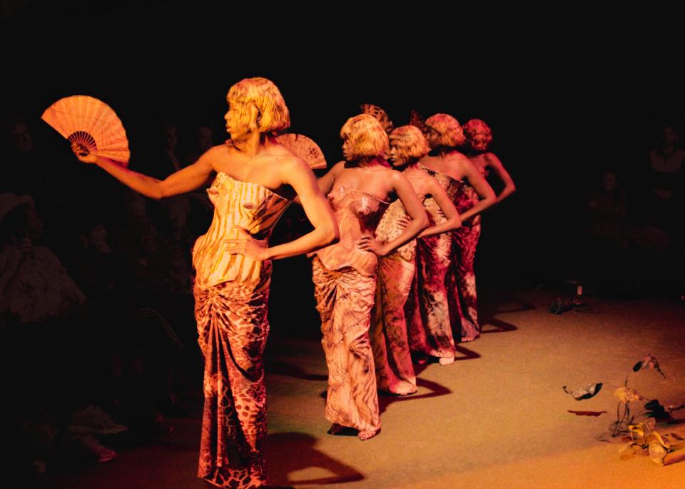 Five people in dresses with fans 