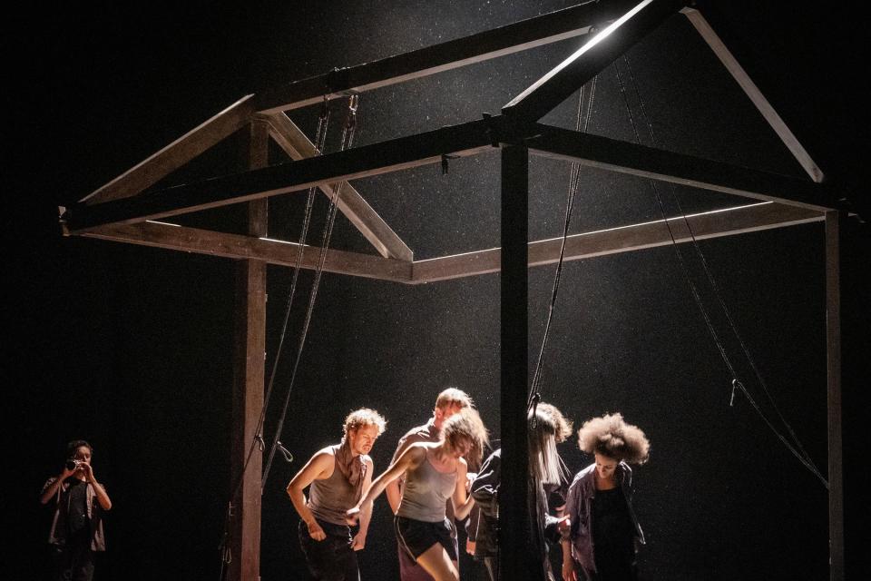 5 performers supporting an open wooden construction