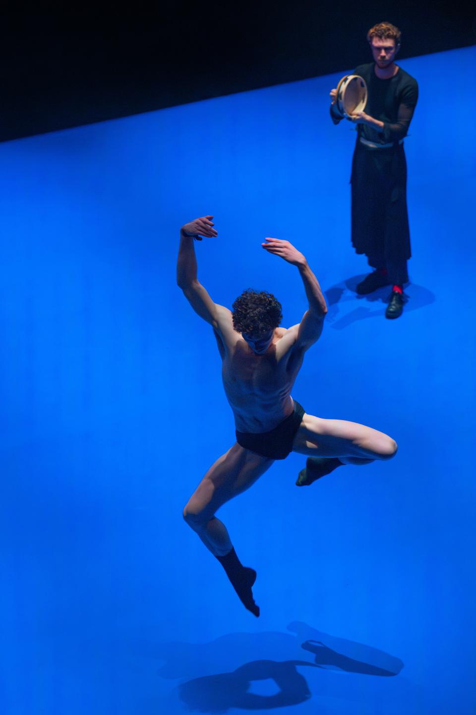 2 performers with black clothes dancing on a bright blue floor