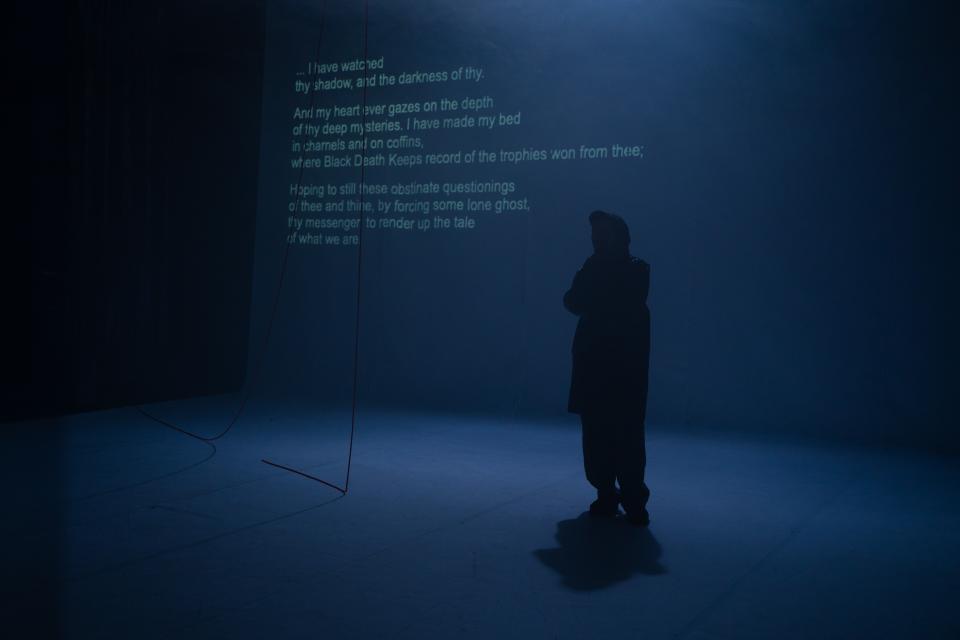 dark figure stands in front of a poem