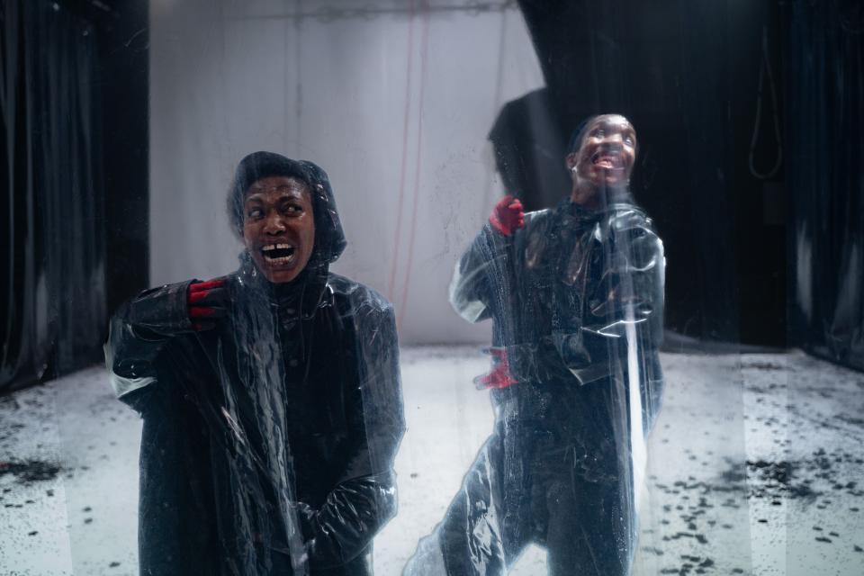 2 dancers in suits behind plastic wall