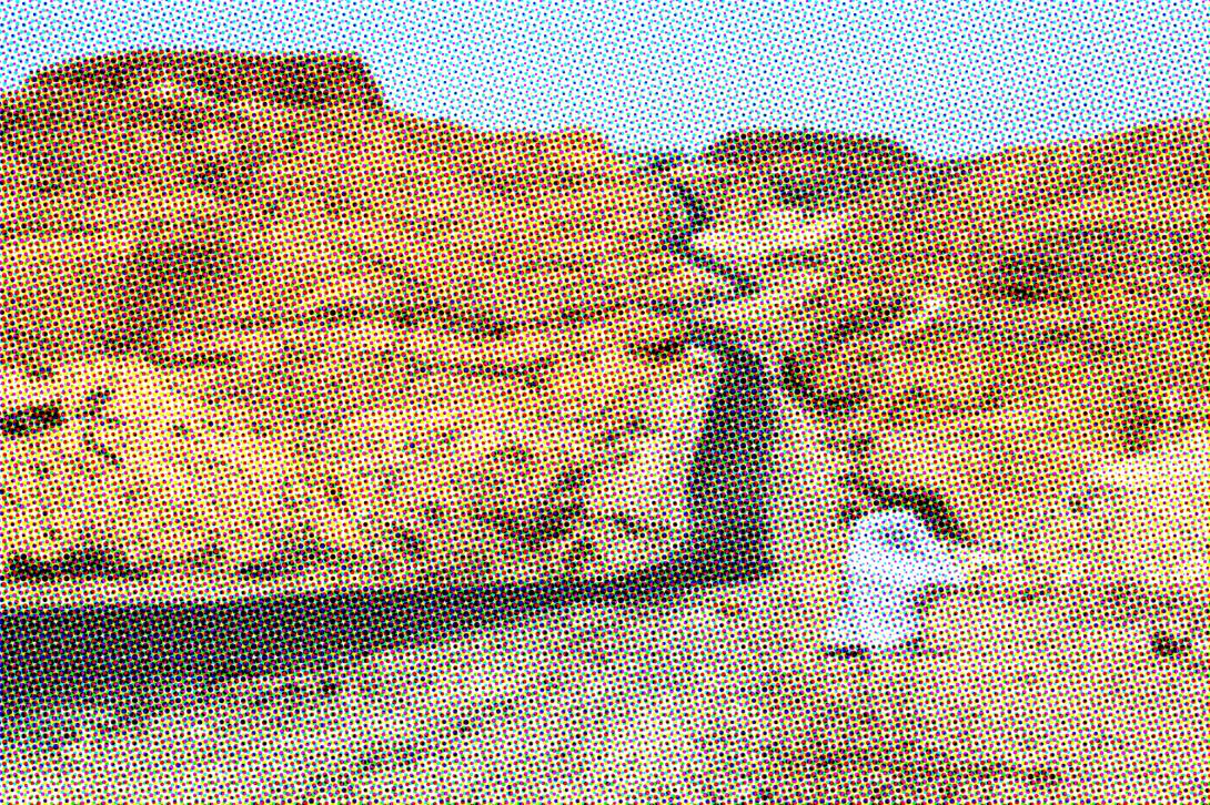 An asphalt road in the desert with a figure wrapped in a white sheet on the side