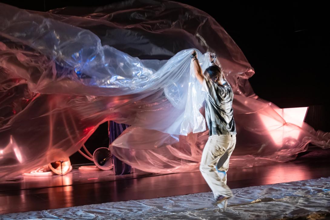 A performer holding up a big plastic screen with both hands