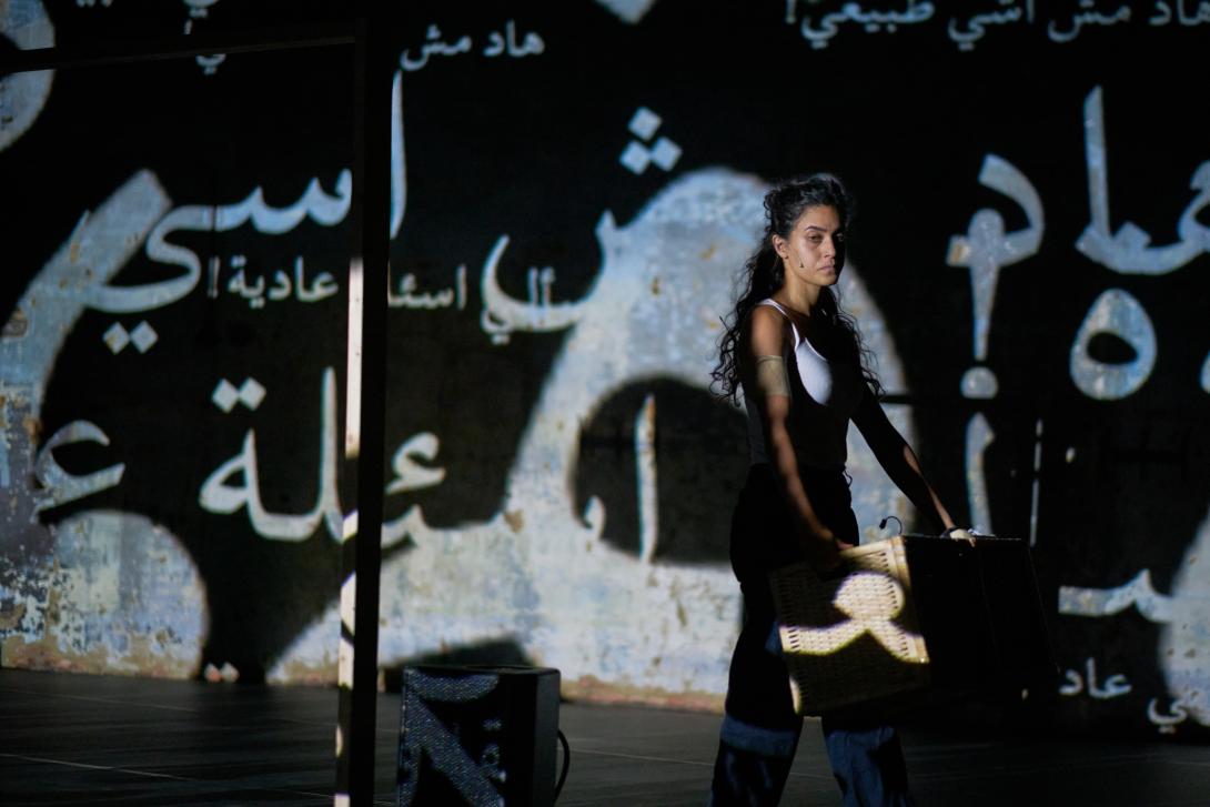 Marah standing in front of a wall with words in Arabic projected on it