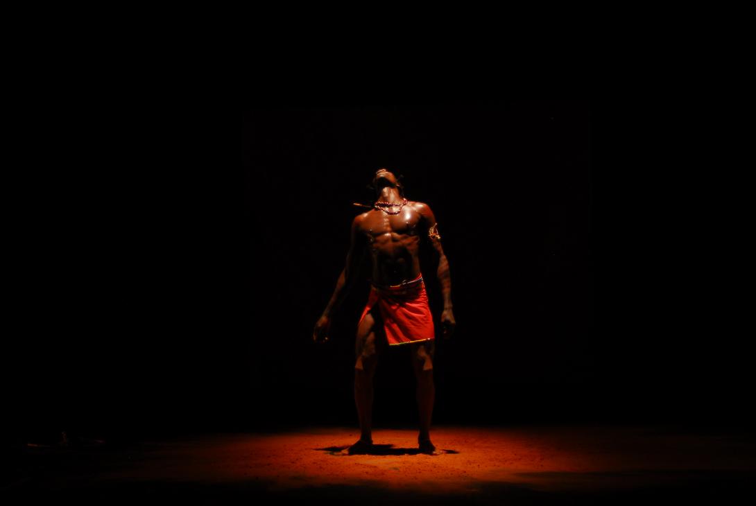 Fernando Anuang'a dressed in traditional Masai clothing under a spotlight