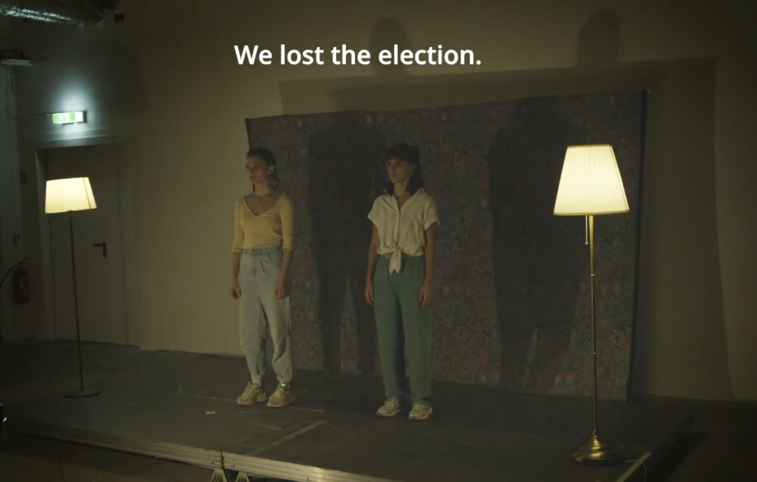 Two women standing in a sparsely lit room underneath the words "We lost the election."