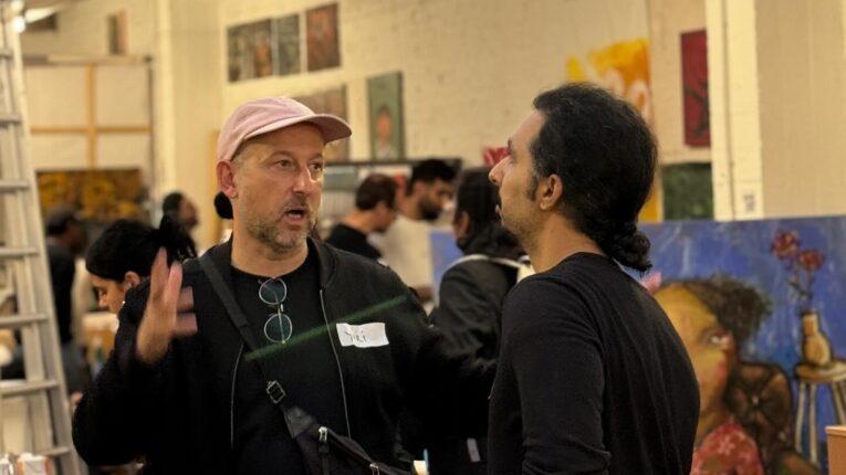 Two people talking in front of several artworks