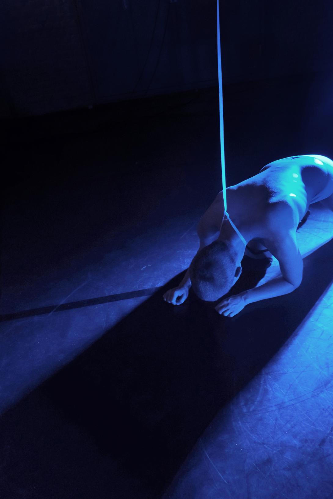 bending naked body covered with blue light