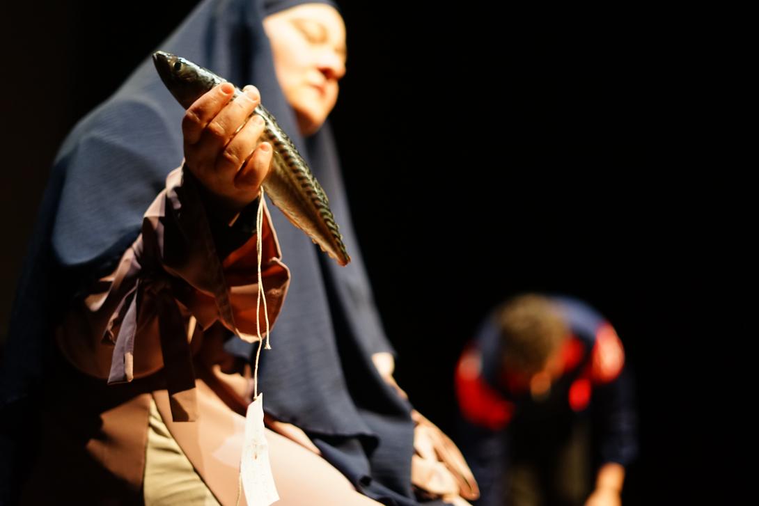 Someone wearing a headdress holding a fish